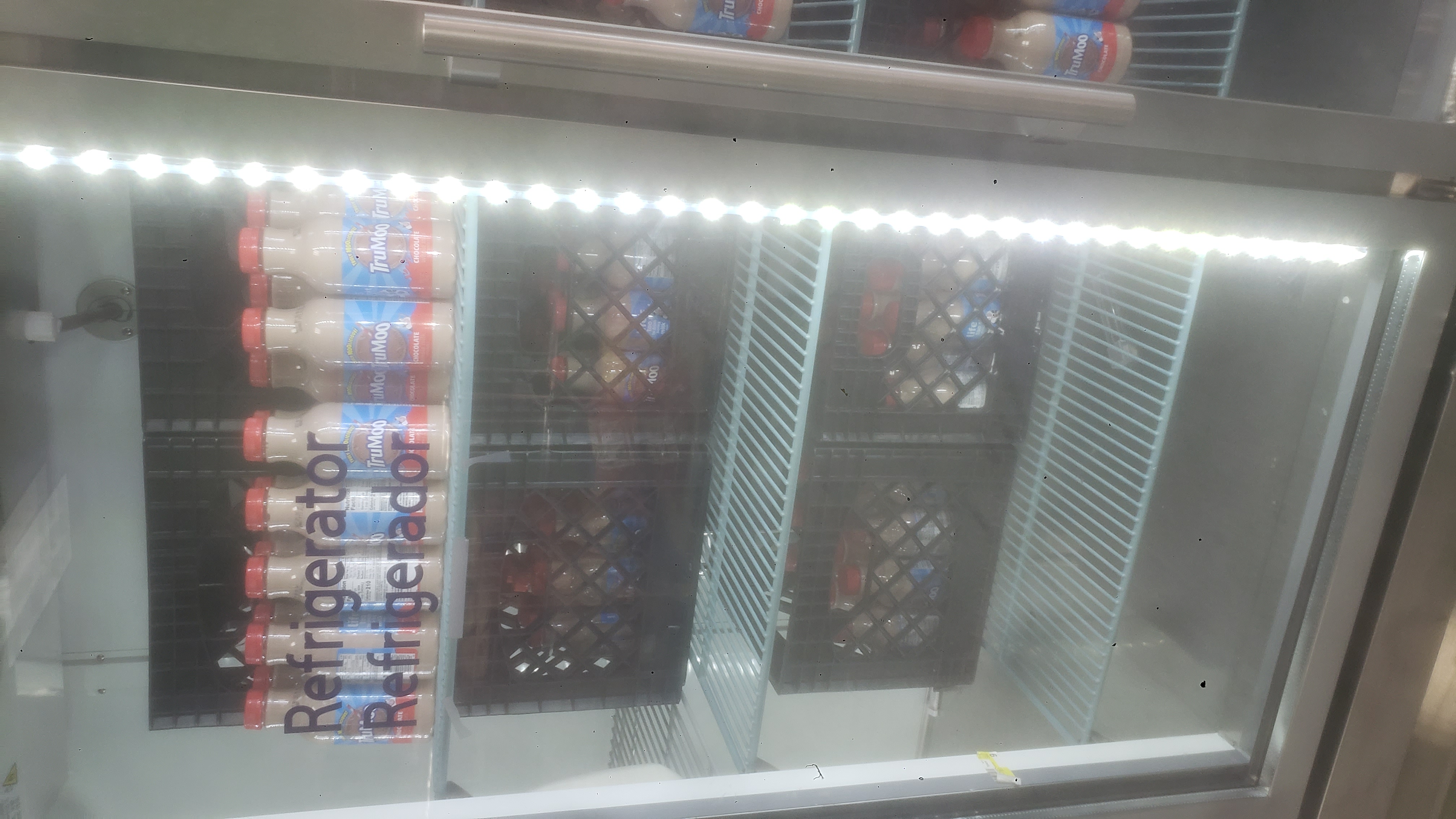 Crates of and bottles of chocolate milk in a fridge.